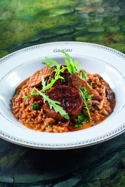 Stinco di maiale al forno: carne da canela de porco ao molho glace sobre risoto agridoce mais folhas de espinafre