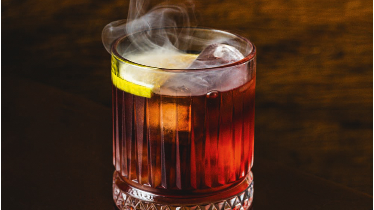 Copo de drinque avermelhado com fumaça saindo.