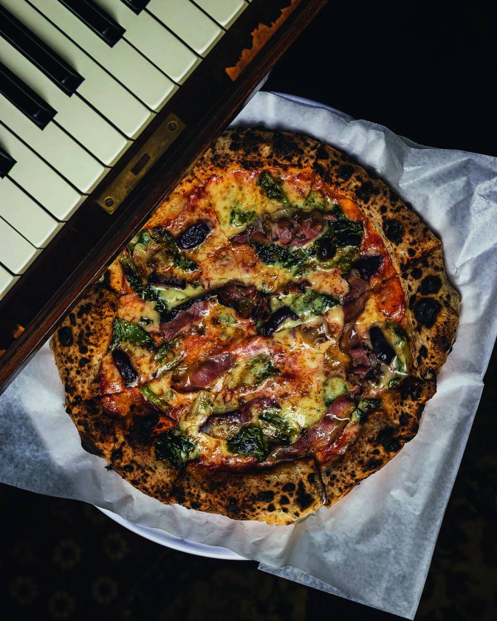Picco Foto aérea de pizza de queijo sobre papel branco com piano ao lado.