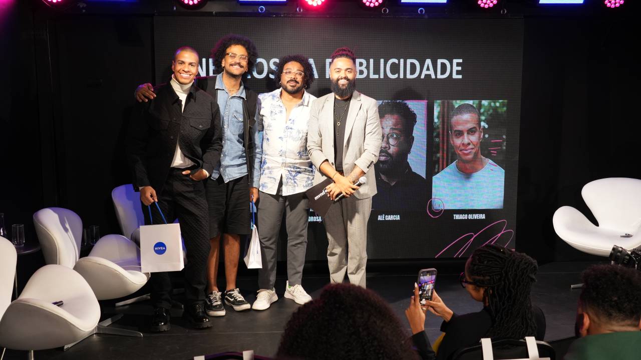 Quatro homens negros posam de pé em palco