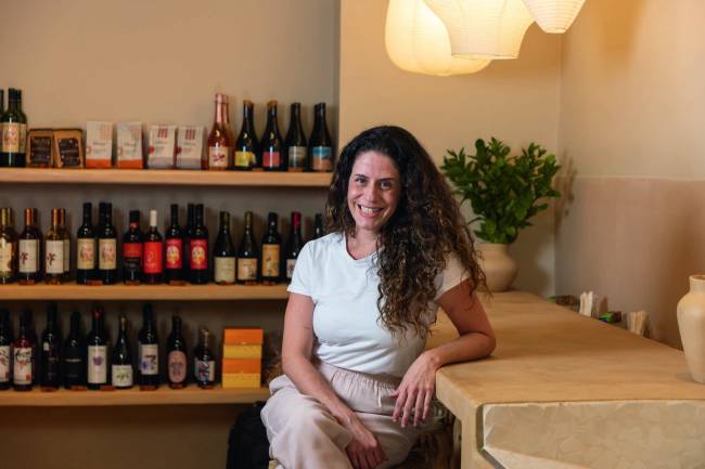 Mulher sentada e encostada em balcão sorrindo