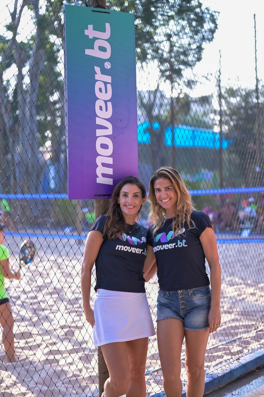 Julie Lamac e sócia Crédito Divulgação Duas mulheres de roupas esportivas sorriem em quadra de beach tennis