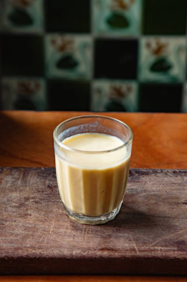 Copo com batida de cachaça em cima de mesa de madeira