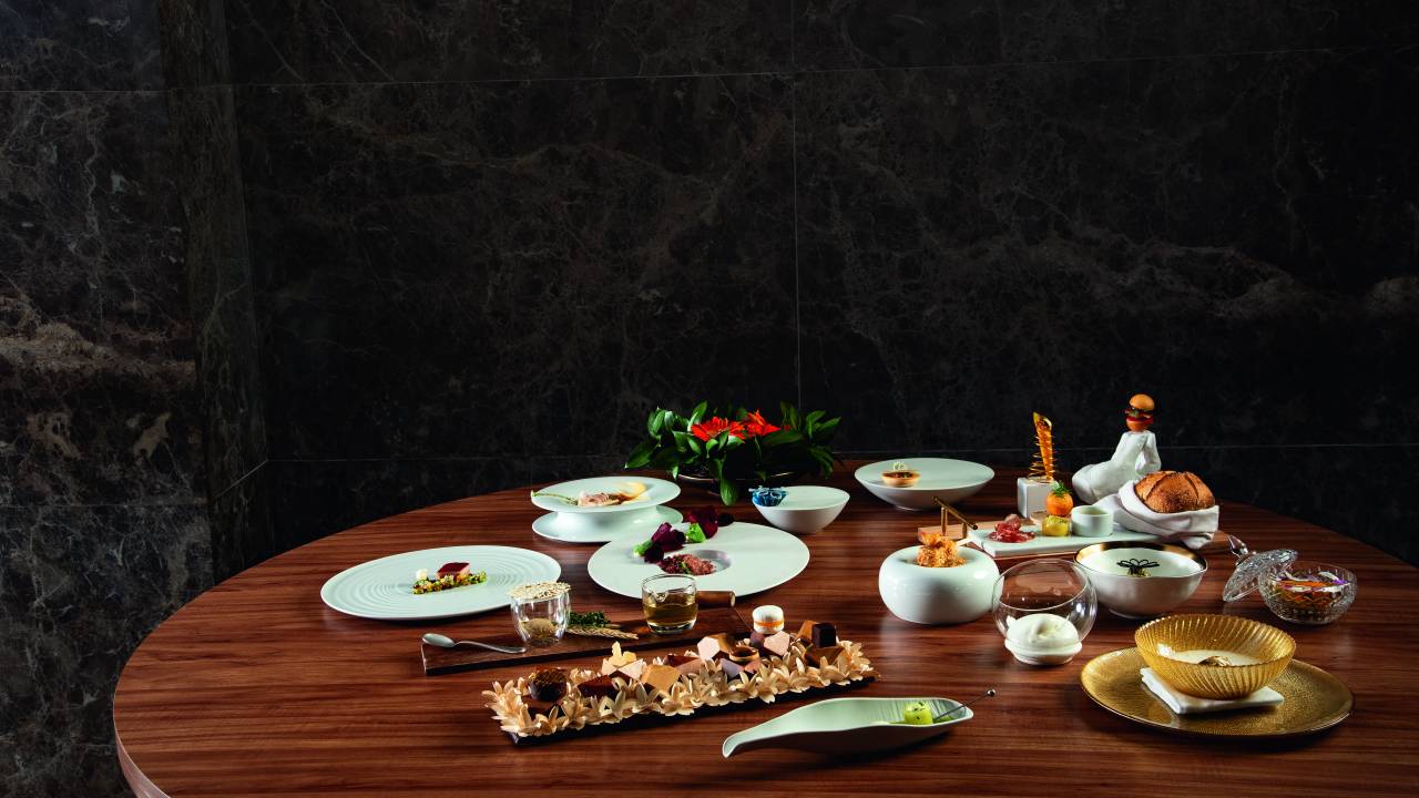 Mesa de madeira posta com menu degustação completo.