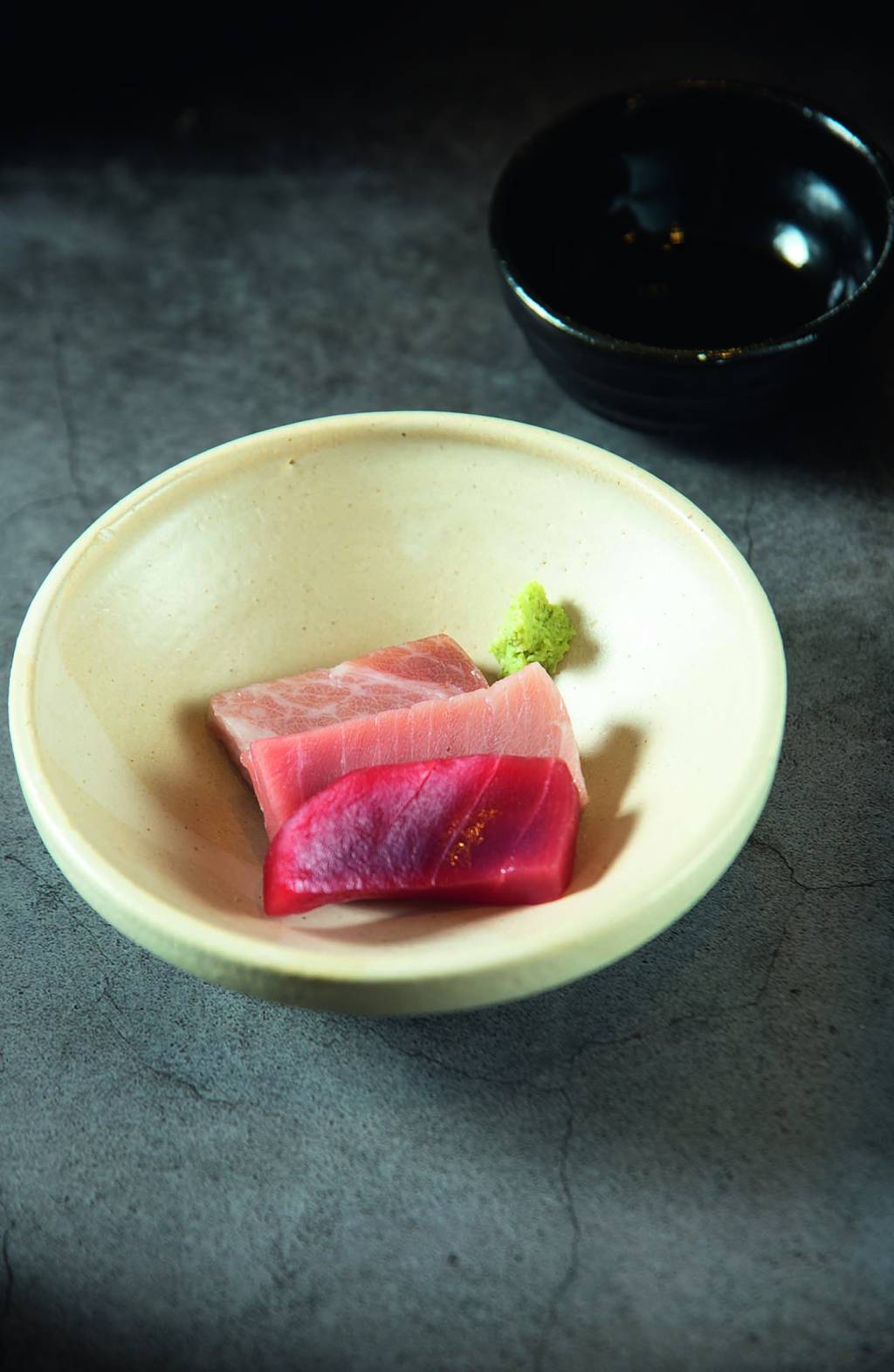 Comer & Beber 2024 – Goya Zushi Tigela de cerâmica branca com três sashimis arroxeados.