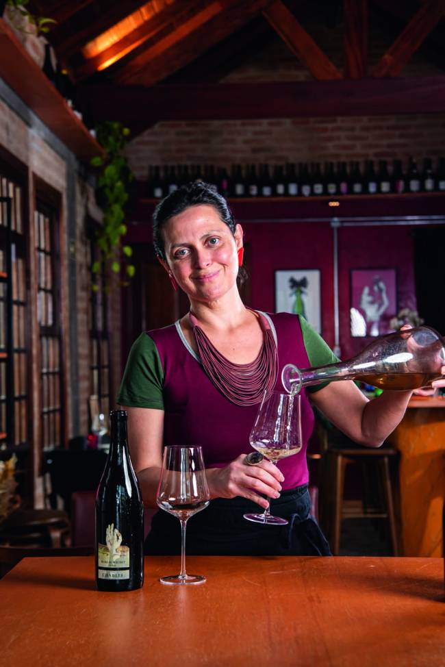 Mulher segurando garrafa e servindo vinho sorrindo