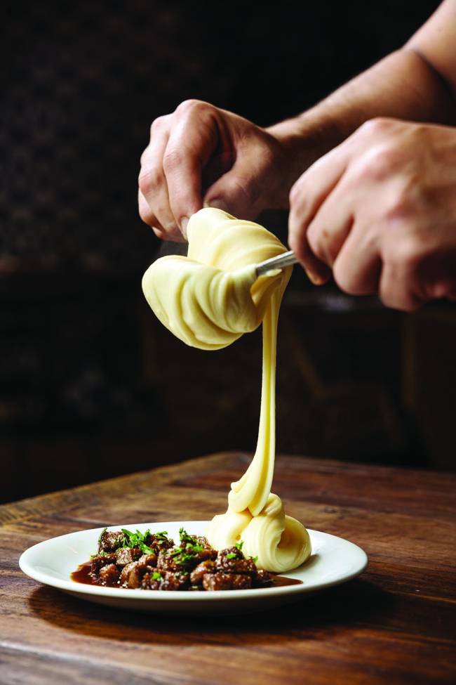 Restaurantes Wanezza Soares D.O.M + Dalva e Dito: aligot com cubos de filé - Isca de pirarucu com molho tártaro = Bolo de coco com a embalagem aberta e fechada Foto Wanezza Soares