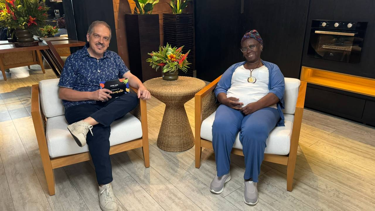 Duas pessoas sentadas em cadeiras e sorrindo