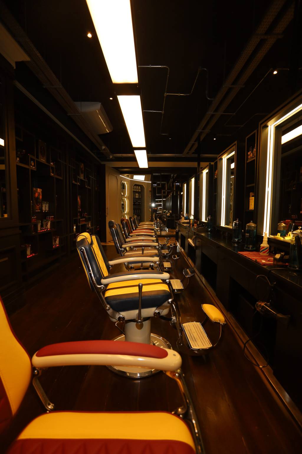 IMG_9351 Sala escura com fileiras de cadeiras coloridas de barbearia