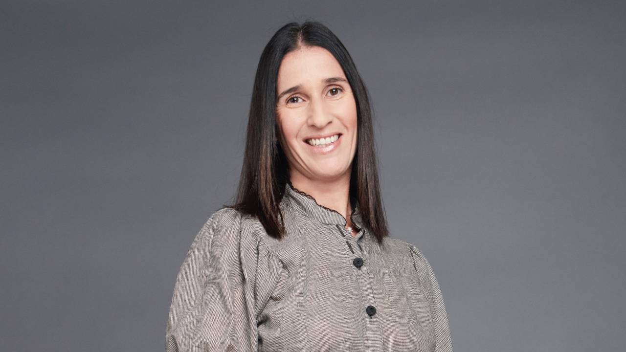 Mulher branca de cabelos longos pretos com vestido cinza