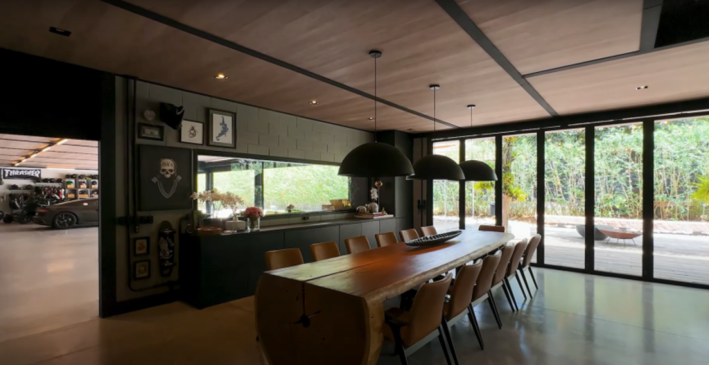 Sala de jantar com grande mesa de madeira e balcão ao fundo