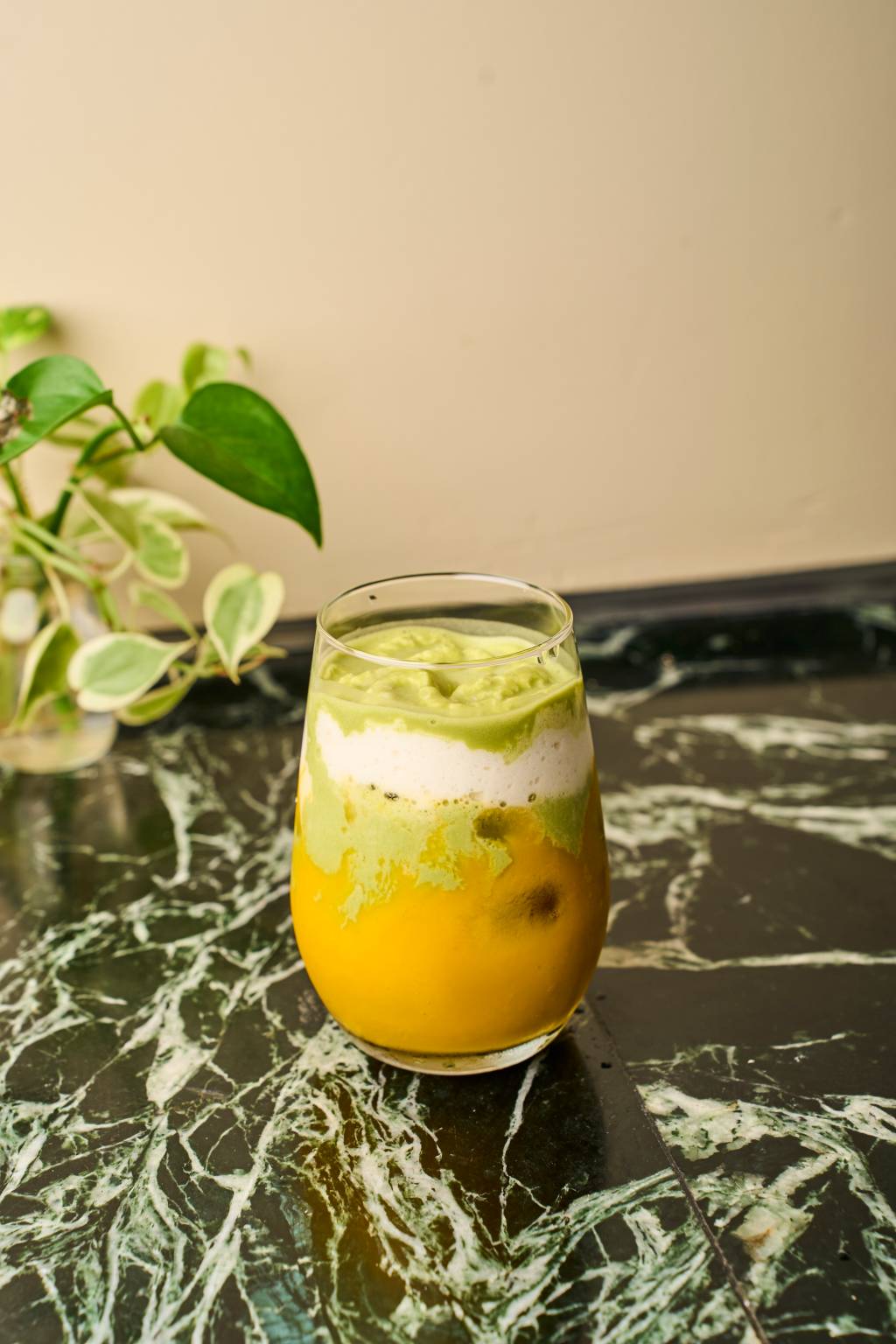 10_botanikafe_julho_lais.acsa Copo com bebida laranja e verde em cima de mesa