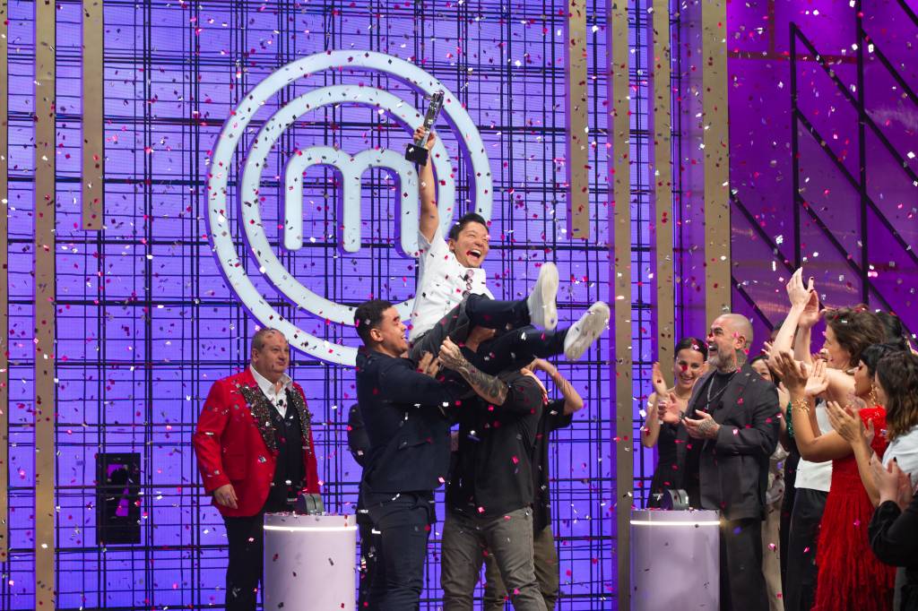 MasterChef Confeitaria 1 O vitorioso Cesar Yukio com o troféu na mão sendo carregado por um grupo de homens
