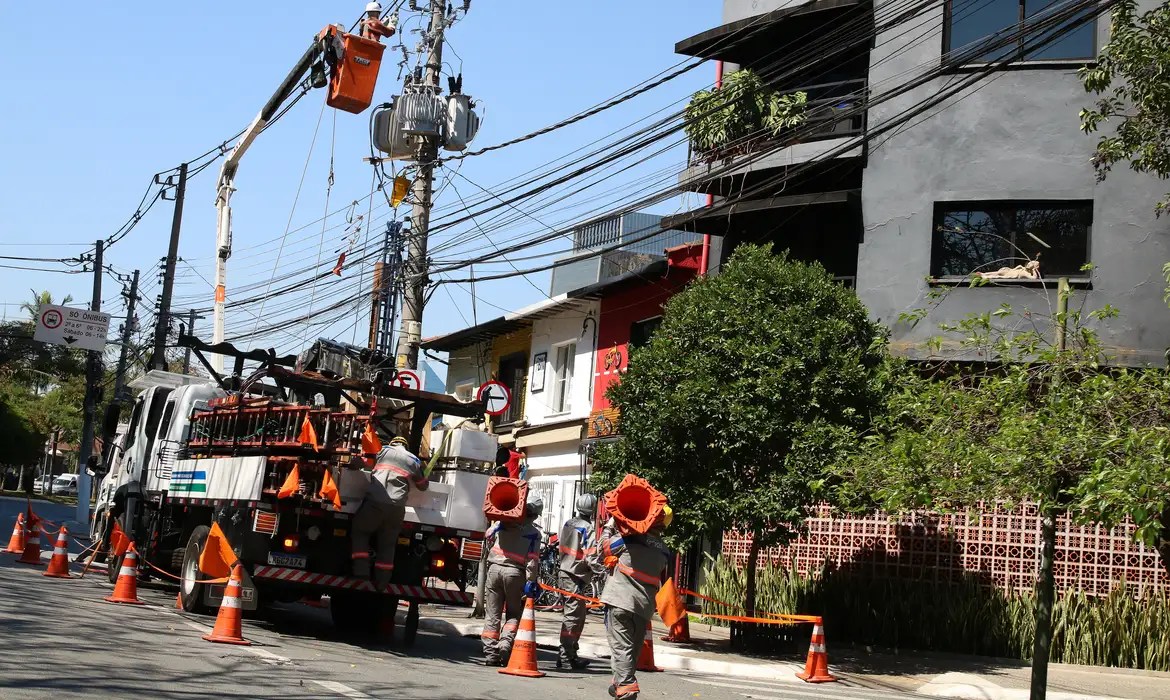 Pessoas trabalhando com caminhão em postes