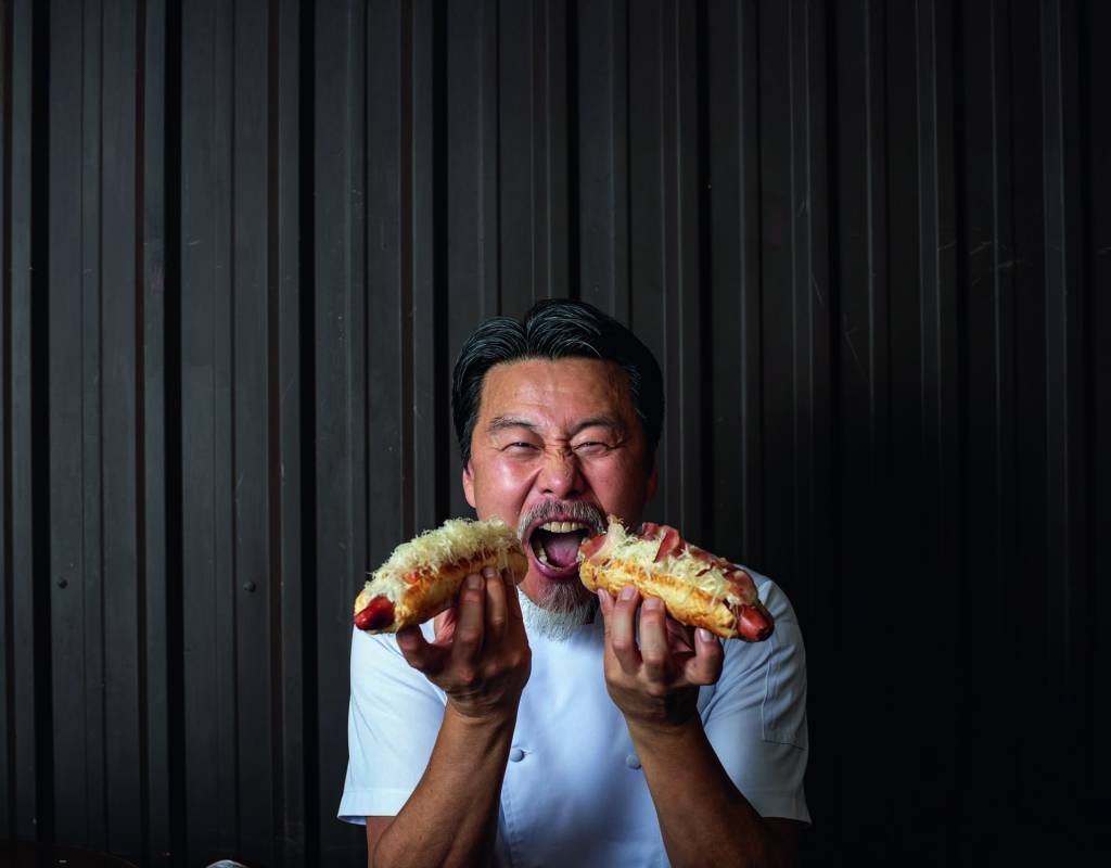 Popa Artesanal Hot Dog Homem com dois sanduíches na mão