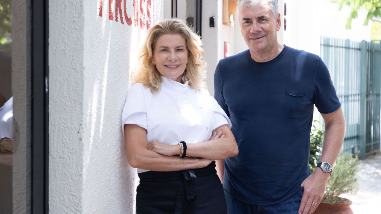 Duas pessoas sorrindo para a foto em parede branca