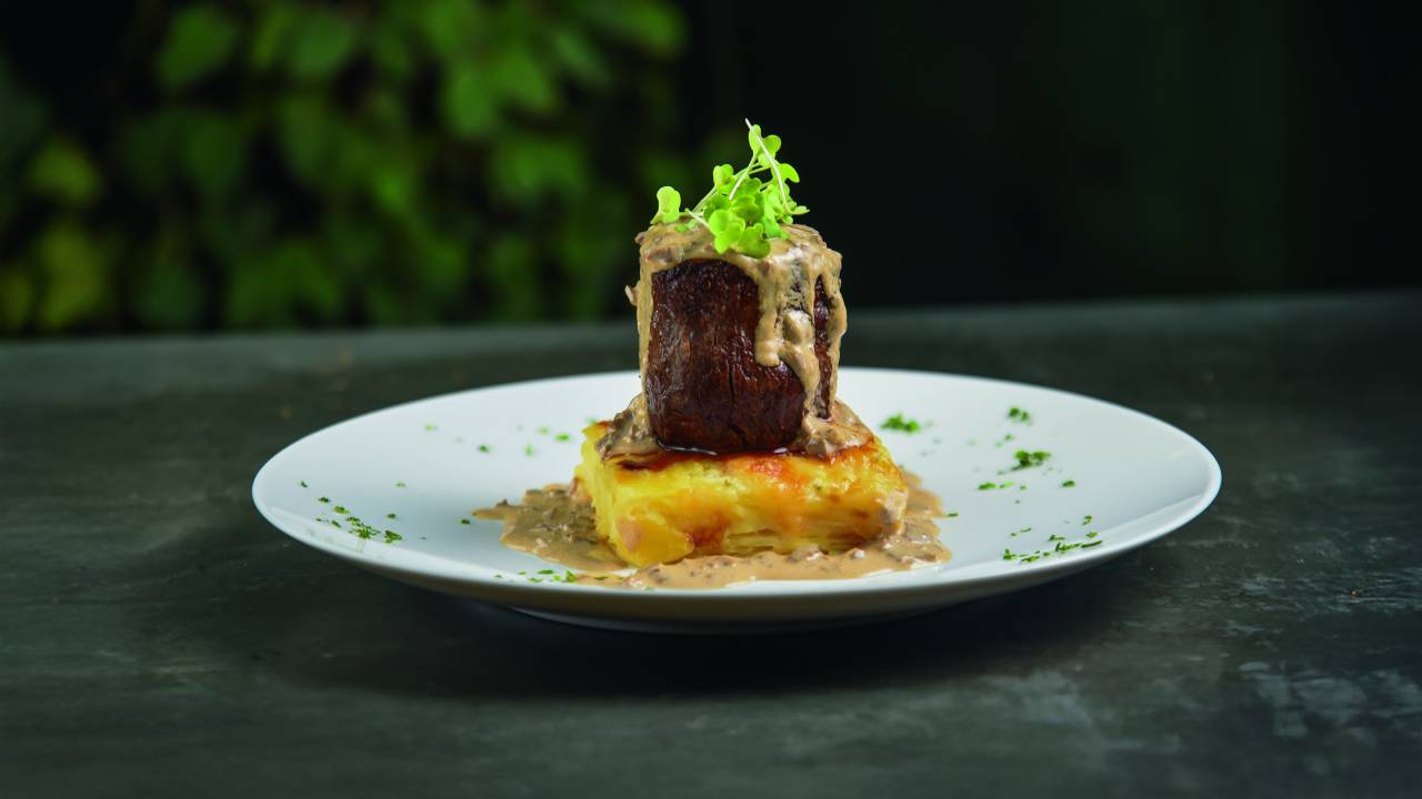 Carne em cima de prato branco com molho