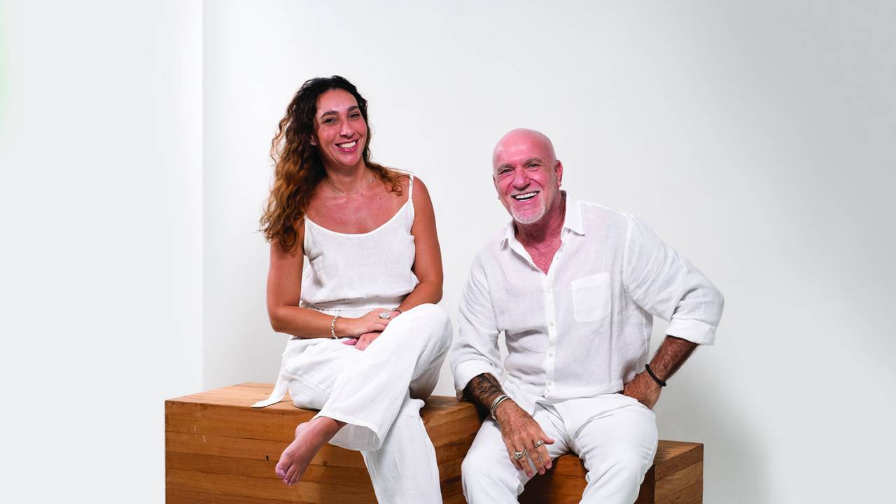 Carol e Gilberto Elkis, ambos de branco em cenário todo branco