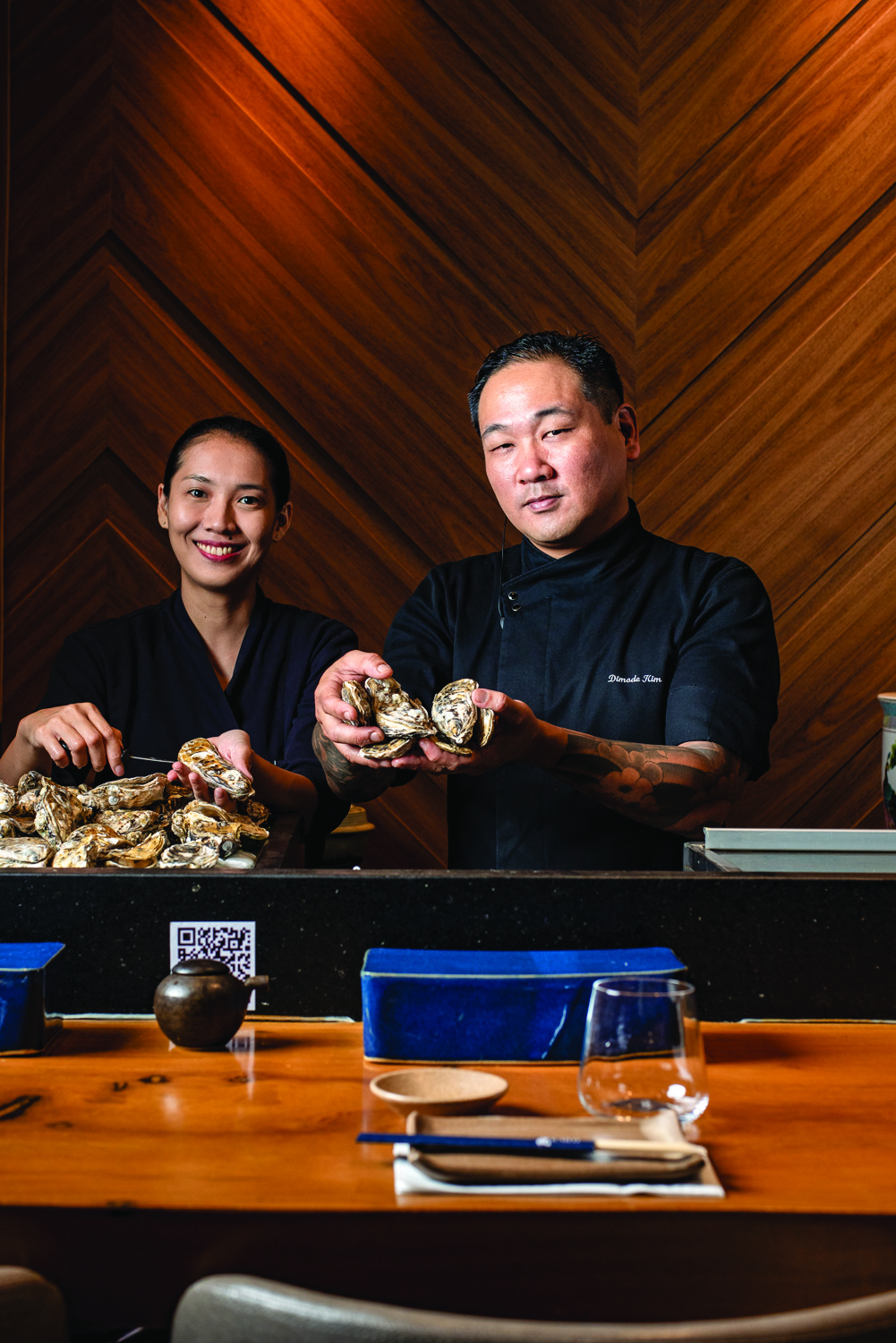 Kaifu Asian Cuisine Duas pessoas sorrindo e pegando itens na mesa