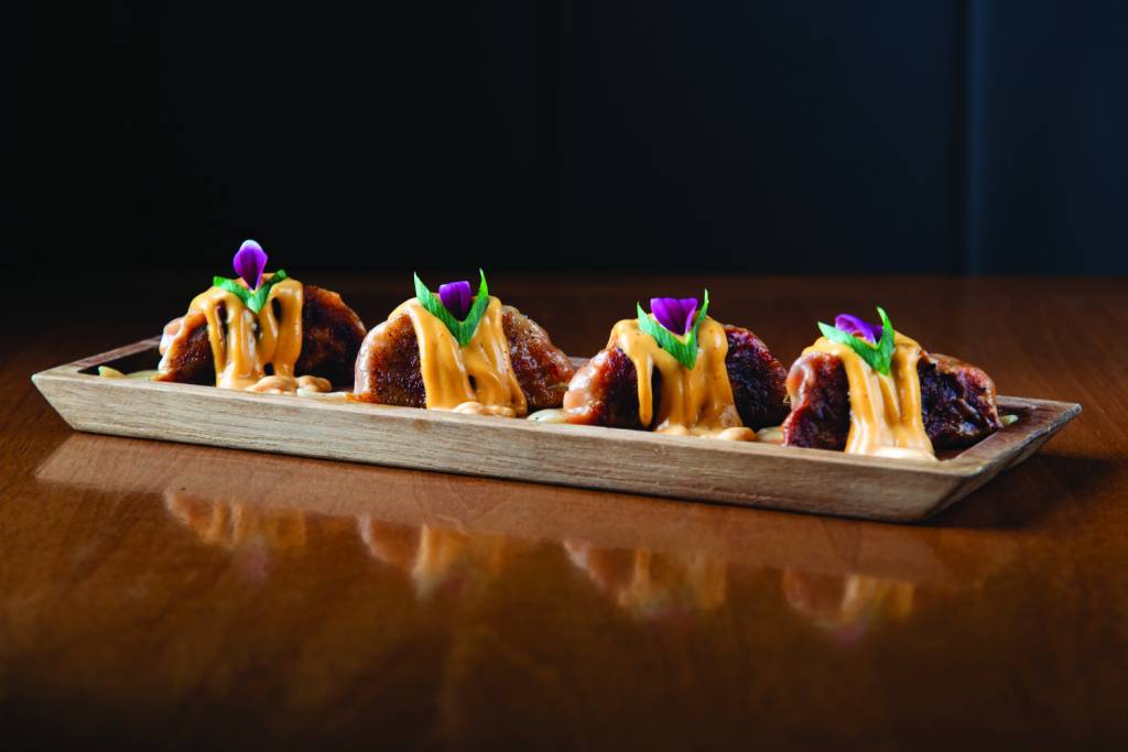 Kaifu Asian Cuisine Guiozas com maionese em cima em prato de madeira