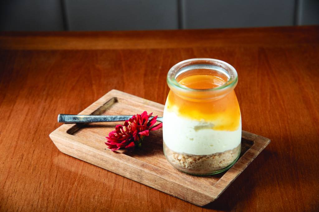 Kaifu Asian Cuisine – Yuzu Cheesecake doce no pote com calda de limão yuzu 037.jpg Sobremesa com yuzu em pote arredondado e flor ao lado