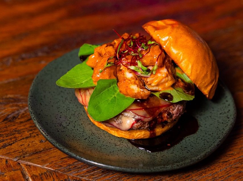 Lierson_Burger Hambúrguer em prato escuro e mesa de madeira