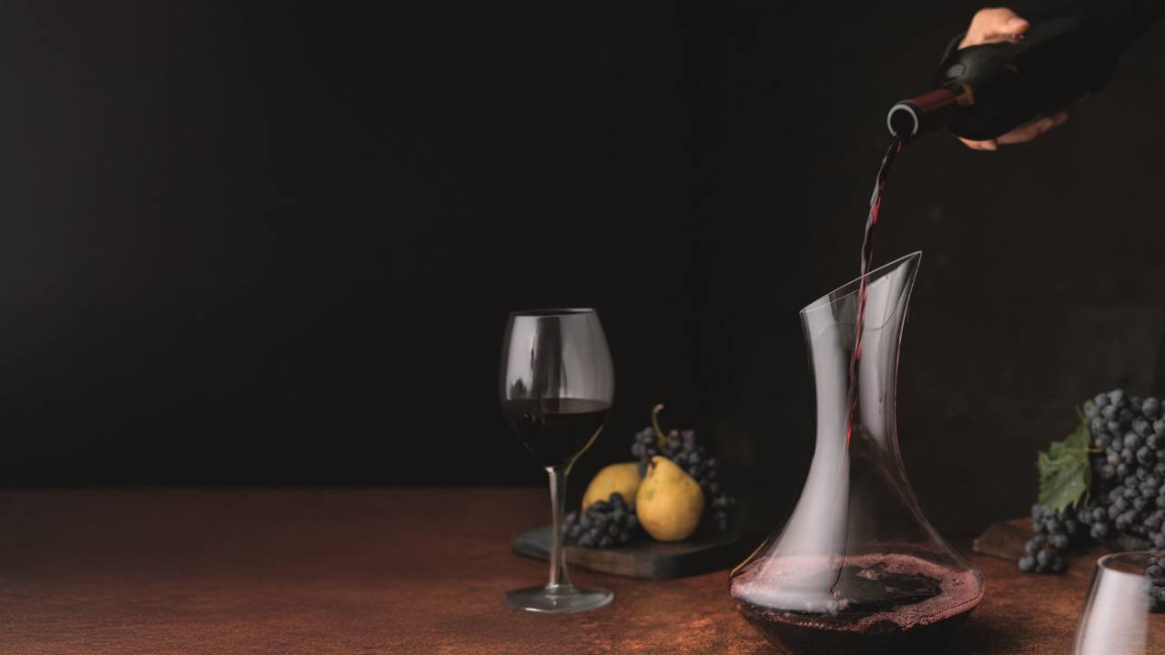 Vinho sendo colocado no decanter e taça ao lado