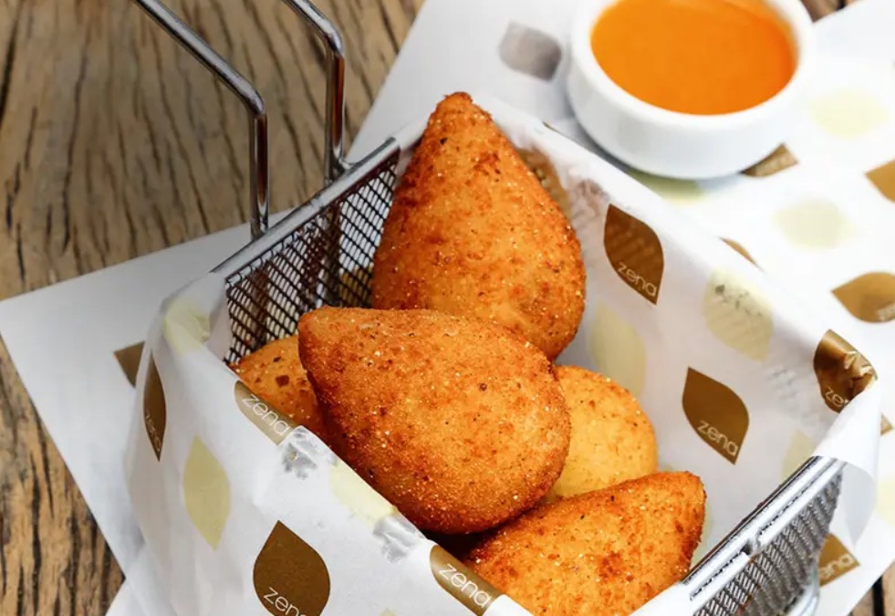 Cestinha com cinco unidades de coxinha e molho ao lado
