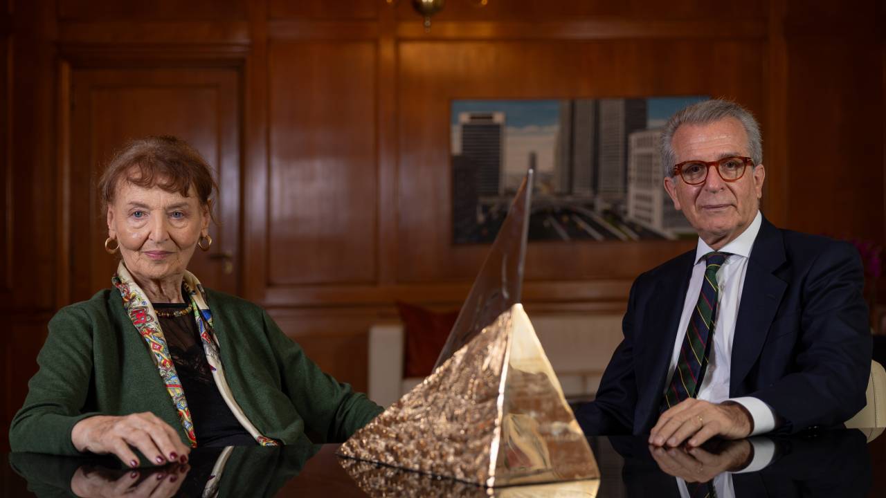 Aurora Bernardini e Andrea Matarazzo sentados com troféu em formato de pirâmide no meio de mesa de madeira
