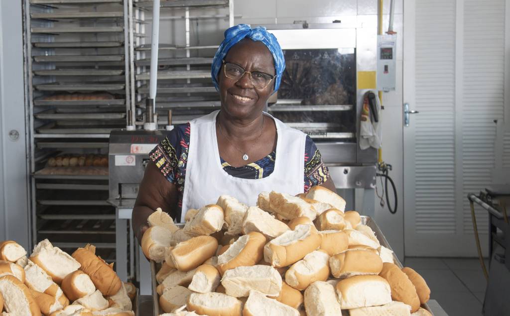 Instituto Ações Sociais Vó Tutu Senhora segurando pães e sorrindo