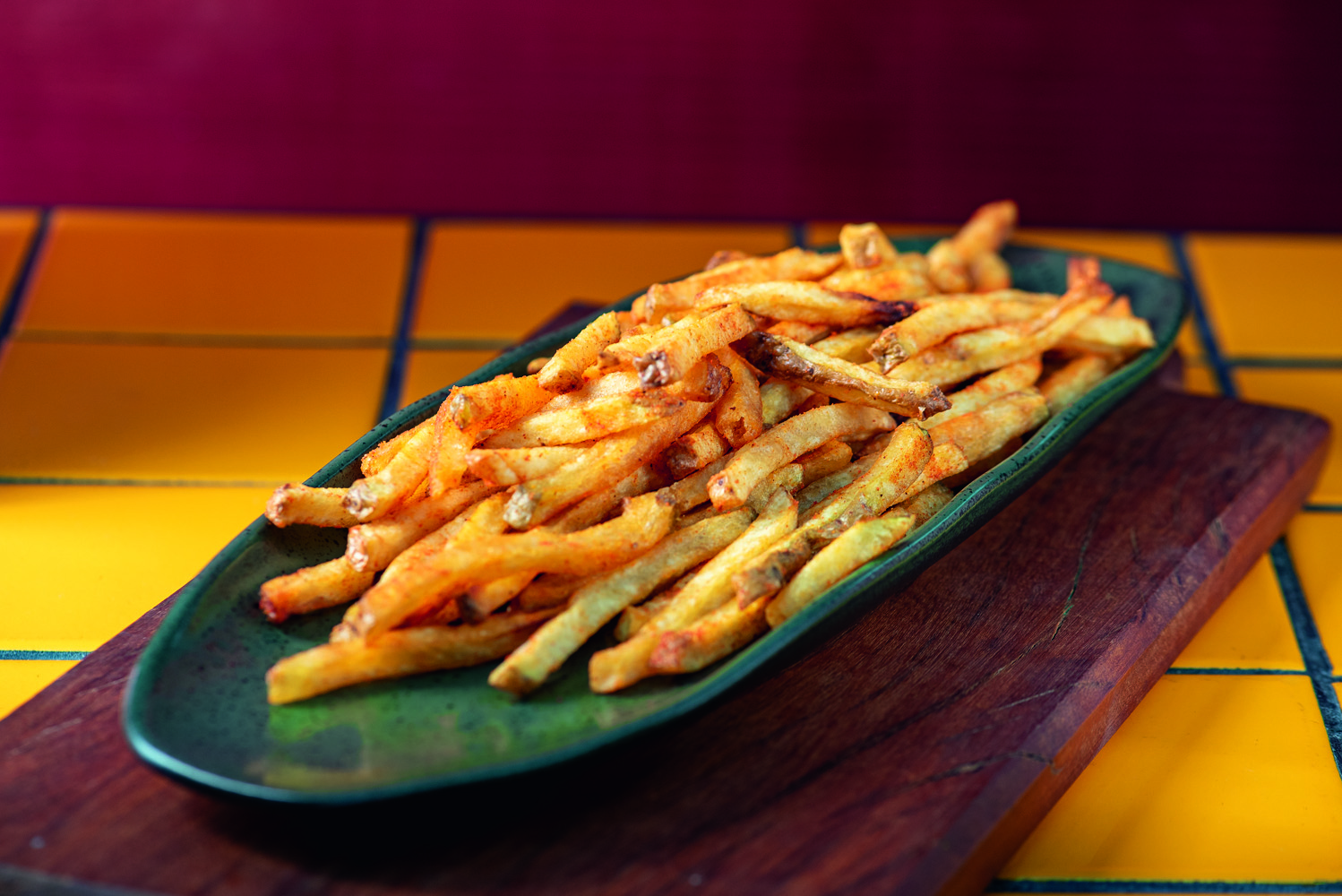 Batata frita em cima de prato verde e mesa amarela