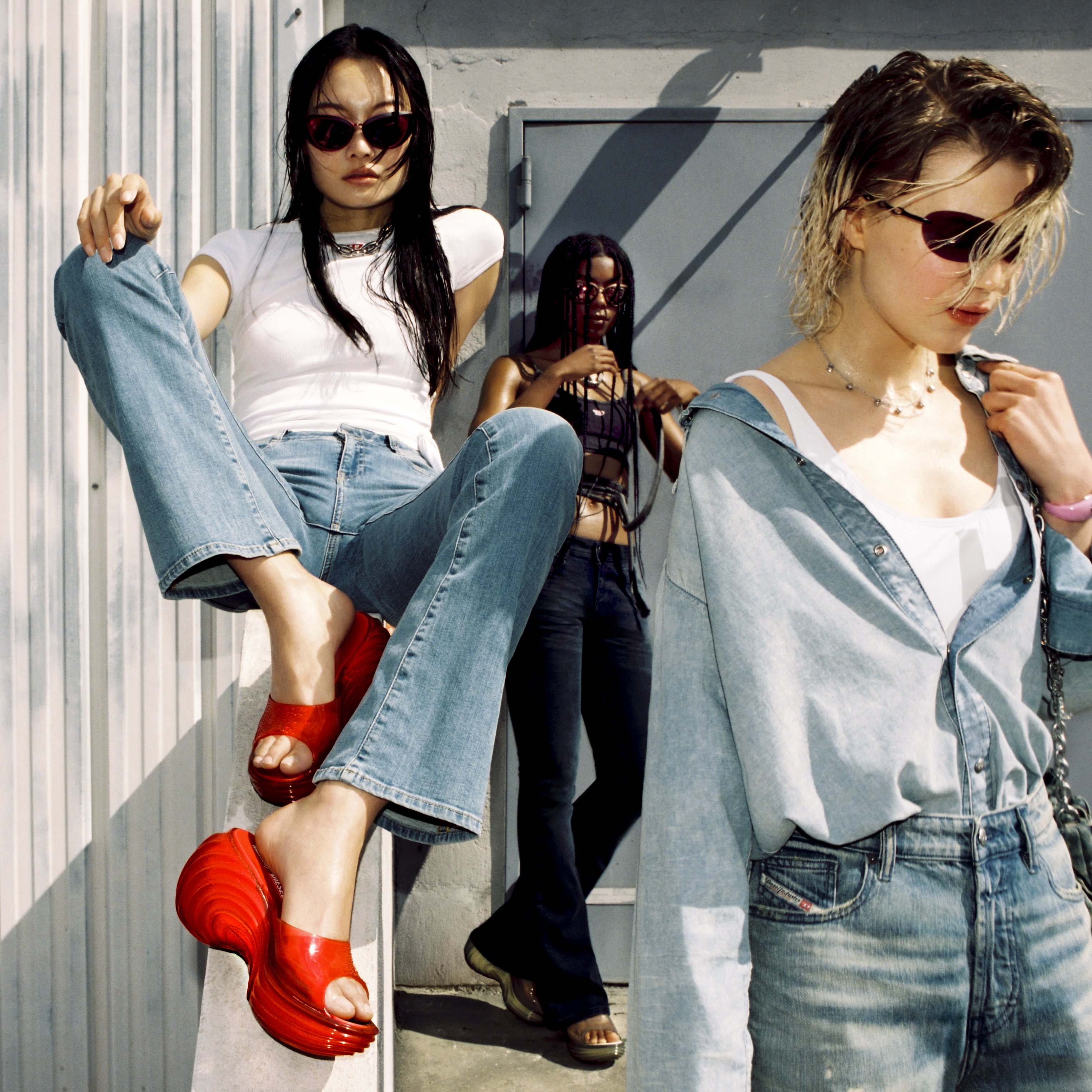 Modelo sentada em batente com sand&aacute;lia vermelha e duas ao lado, uma de preto, a outra de jeans, todas de &oacute;culos de sol
