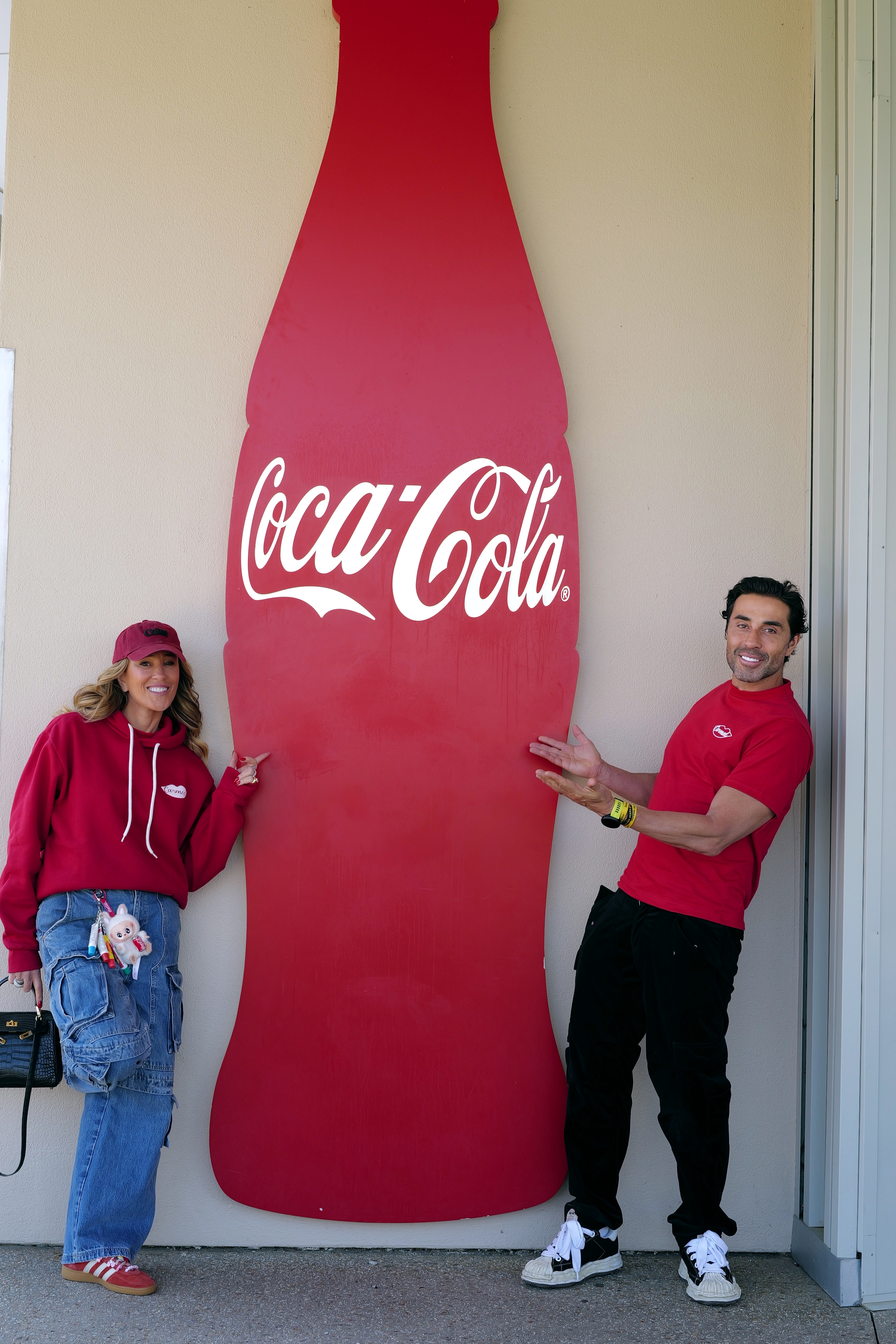 Karla Marques Felmanas e Jo&atilde;o Adibe, da Cimed, em frente a grande logo da Coca em formato de garrafa