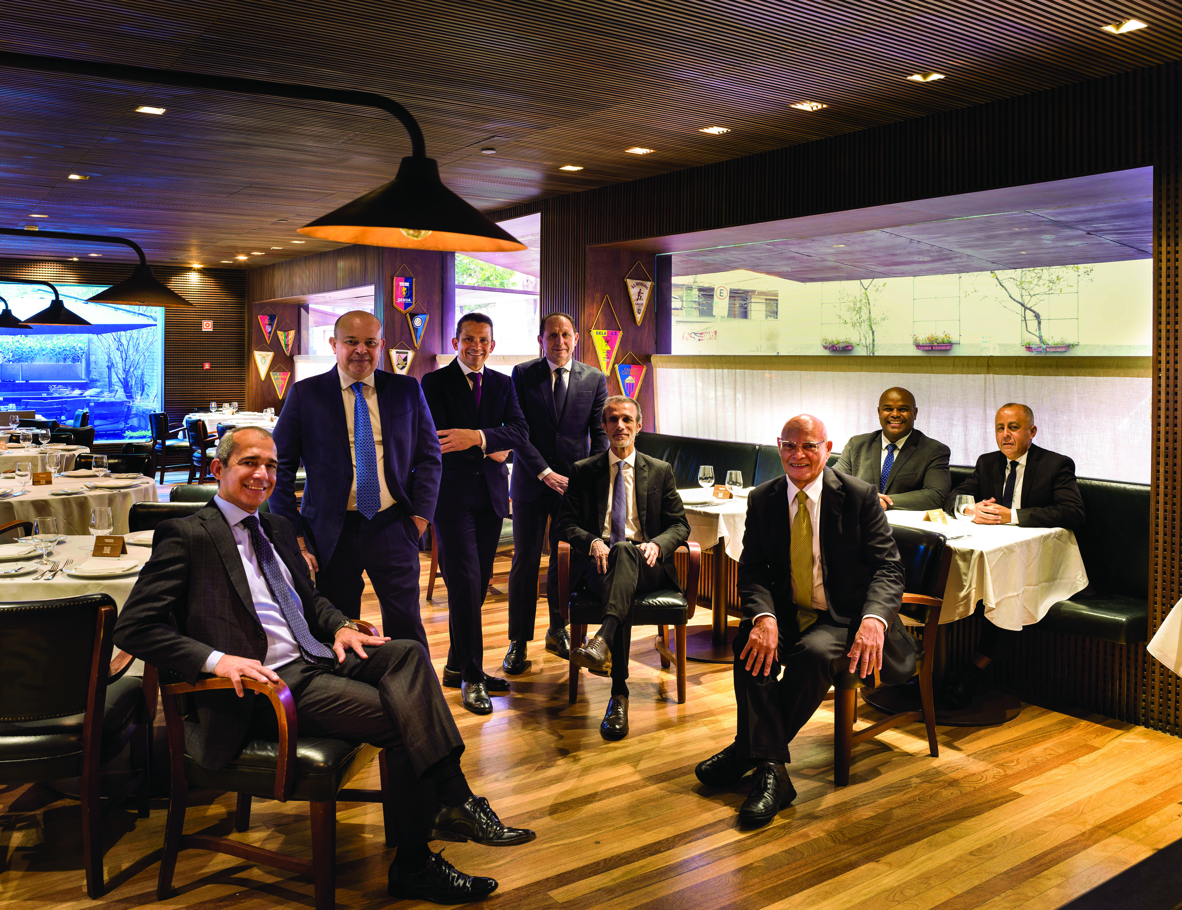 Homens sorrindo em um sal&atilde;o com cadeiras e mesas