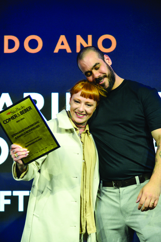 Casal abra&ccedil;ado e sorrindo com placa