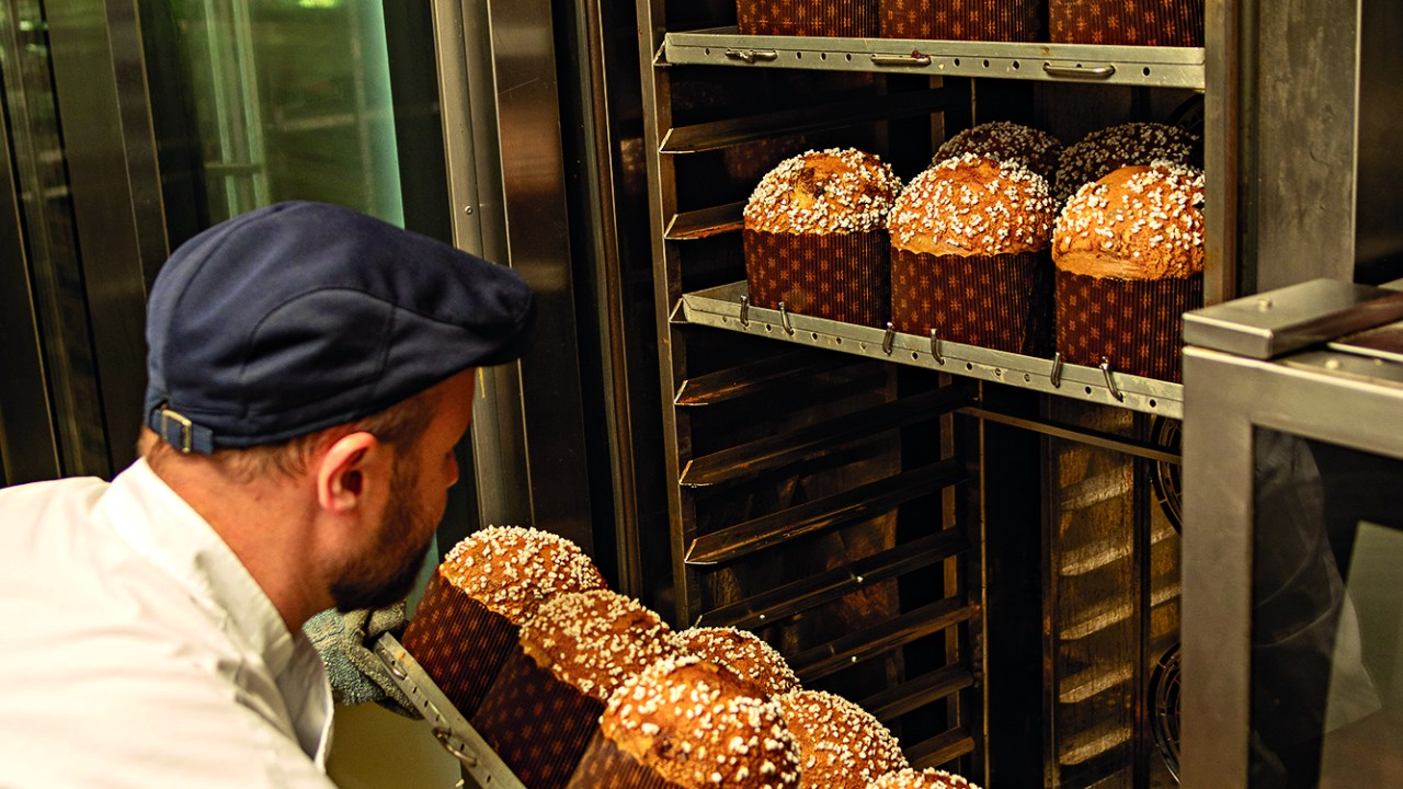 Homem colocando panetone no forno