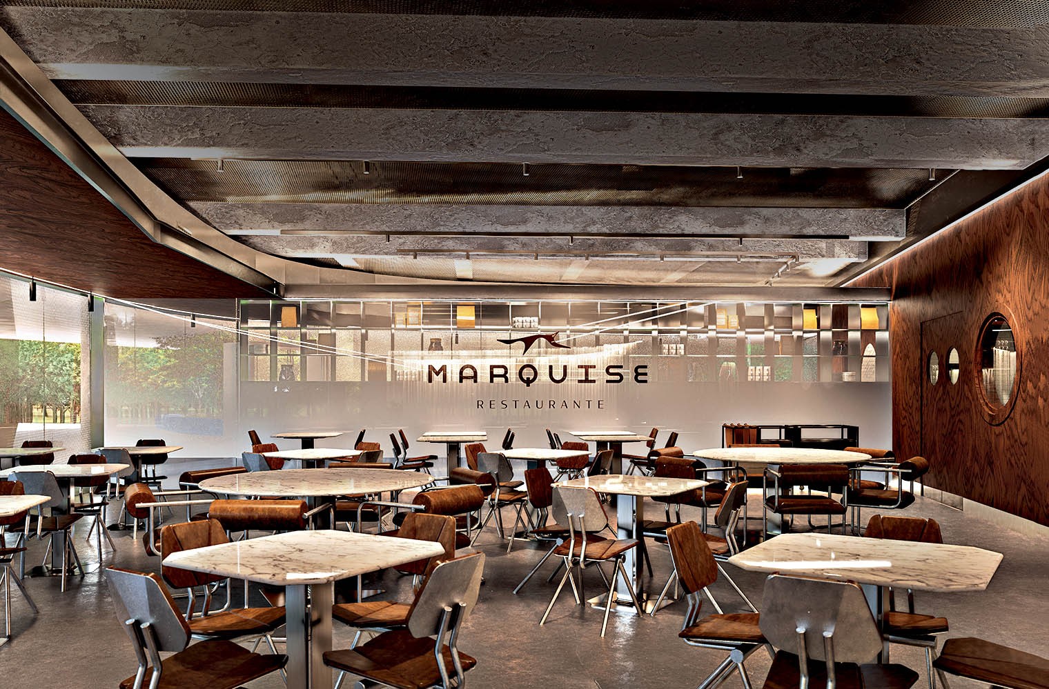 Interior de um restaurante moderno e espa&ccedil;oso, com mesas de m&aacute;rmore e cadeiras de madeira e estofamento marrom. O teto tem vigas expostas e ilumina&ccedil;&atilde;o discreta. Ao fundo, uma parede branca exibe o nome MARQUISE RESTAURANTE em letras escuras, com uma silhueta de p&aacute;ssaro. &Agrave; direita, uma parede de madeira escura com janelas redondas. &Agrave; esquerda, grandes janelas de vidro revelam &aacute;rvores verdes