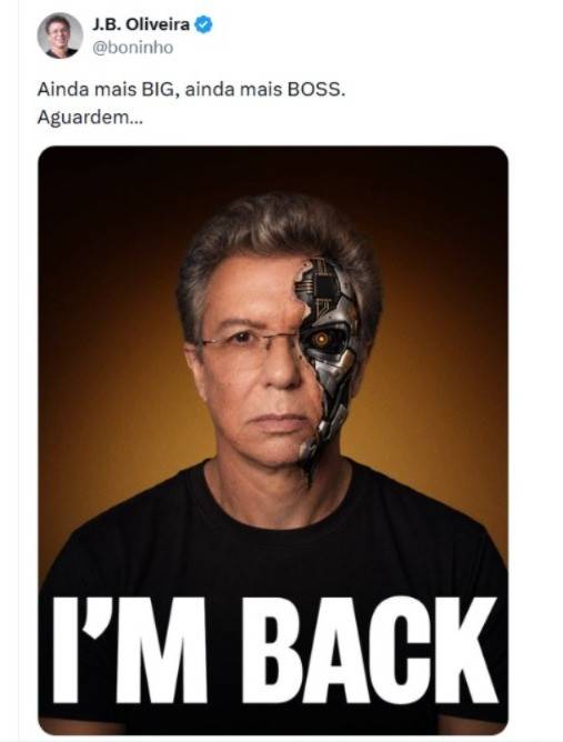 Homem de meia-idade com cabelo grisalho e &oacute;culos, usando camiseta preta com a frase IM BACK em branco. O lado direito do seu rosto &eacute; uma imagem de ciborgue, com partes met&aacute;licas e um olho brilhante. O fundo &eacute; marrom escuro. Acima, um tweet de J.B. Oliveira (@boninho) diz: Ainda mais BIG, ainda mais BOSS. Aguardem...